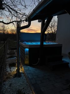 Szentendrei Öregvíz Vendégház jakuzzi a teraszon esti fényekben.